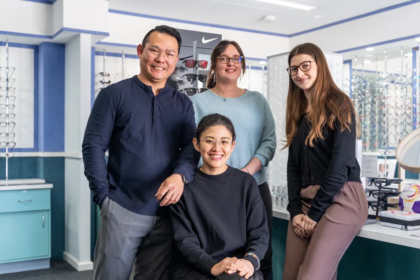 The team at E Eye Place Newing & Co in front of the frames wall at the Shelley clinic