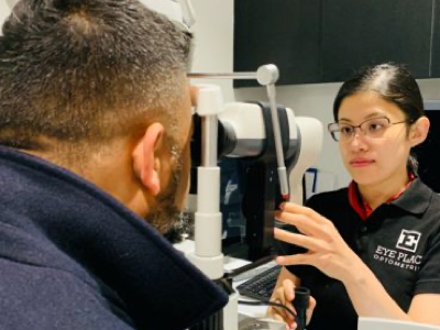 optometrist conducting an comprehensive eye test on customer