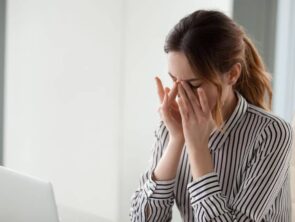 A woman gently wiping her eyes due to discomfort or soreness