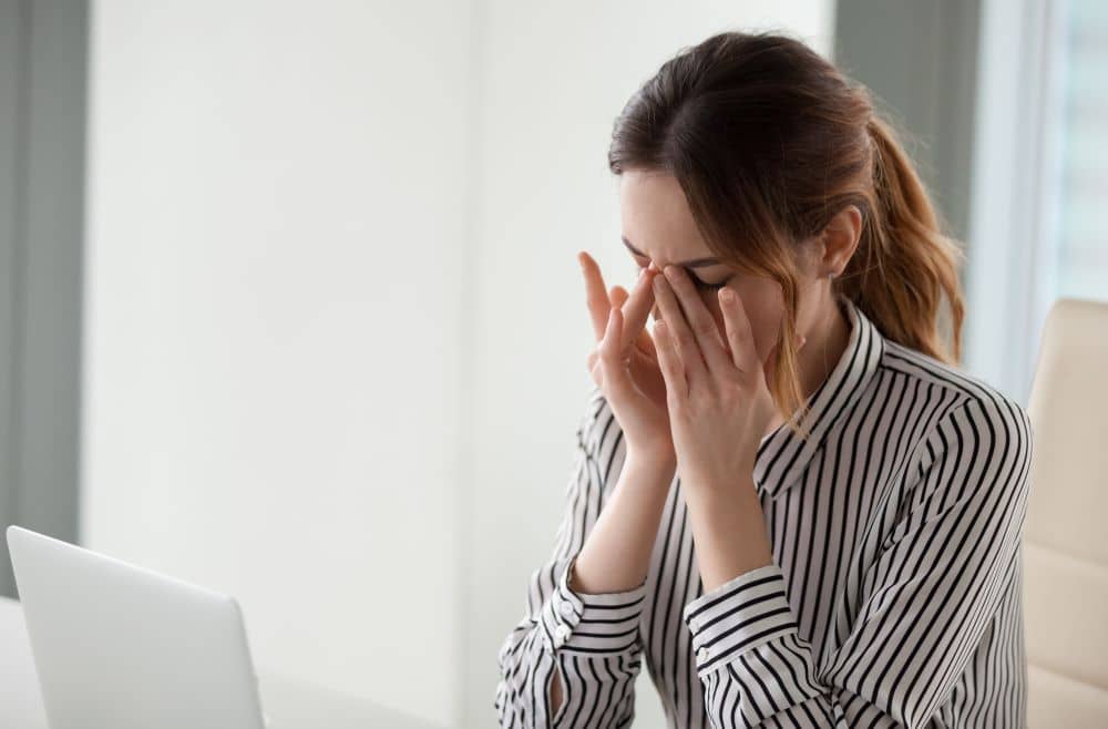 A woman gently wiping her eyes due to discomfort or soreness