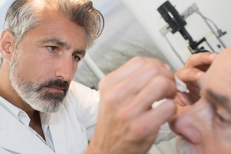 Doctor putting eye drops into a patients eyes to help manage dry eye symptoms