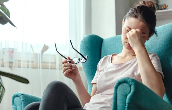 Woman with headache, taking off eyeglasses.
