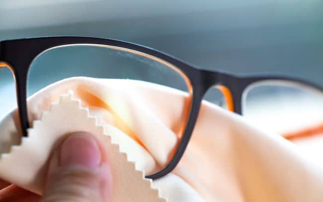 Gently rub the lenses with an optical quality microfiber cloth (if it's not optical quality then it's probably not suitable for coated lenses), moving in circular motions to avoid scratches.